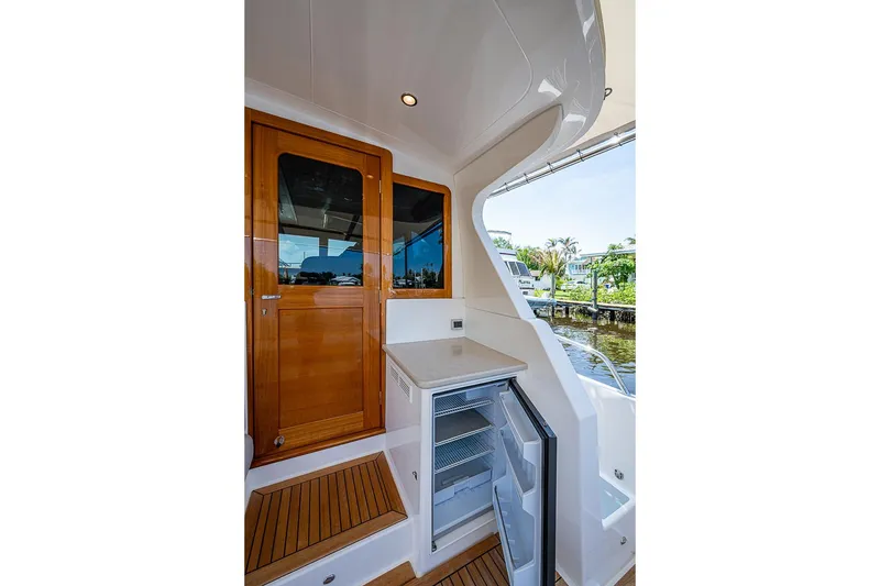 Slide: The Image of 2024 Grand Banks 44 Eastbay yacht interior with wooden door and open mini-fridge. - 14
