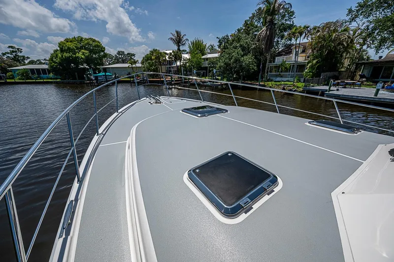 Slide: The Image of 2024 Grand Banks 44 Eastbay yacht deck with hatches, docked by lush greenery. - 15