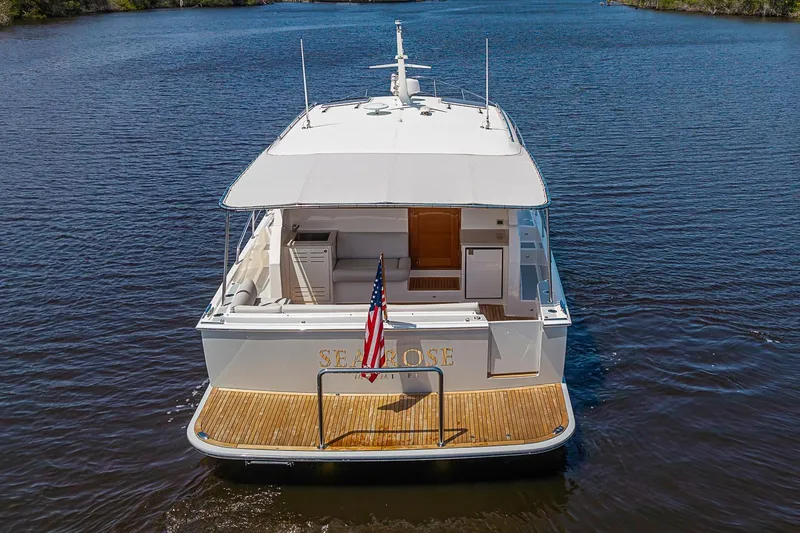 Slide: The Image of 2024 Grand Banks 44 Eastbay yacht on calm water, rear view with American flag. - 38
