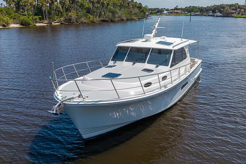 Slide: The Image of 2024 Grand Banks 44 Eastbay yacht cruising on a serene river with lush greenery. - 40