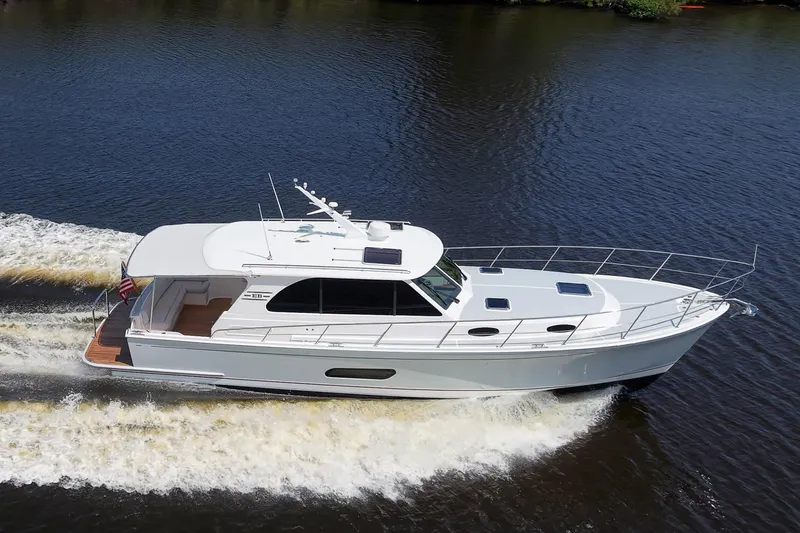 Slide: The Image of 2024 Grand Banks 44 Eastbay cruising on a calm river, showcasing sleek design and performance. - 6