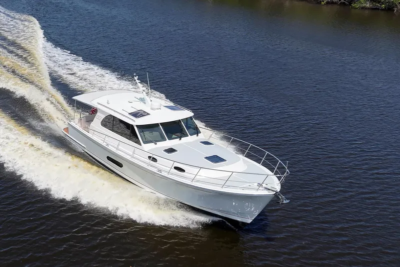 Slide: The Image of 2024 Grand Banks 44 Eastbay cruising on a calm river, showcasing sleek design and performance. - 7