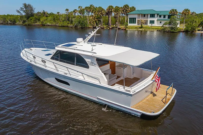 Slide: The Image of 2024 Grand Banks 44 Eastbay yacht cruising on a serene river near a luxurious house. - 8