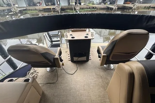 Slide: The Image of 2023 Barletta Cabrio 24CC boat interior with seating and table, docked by the water. - 19