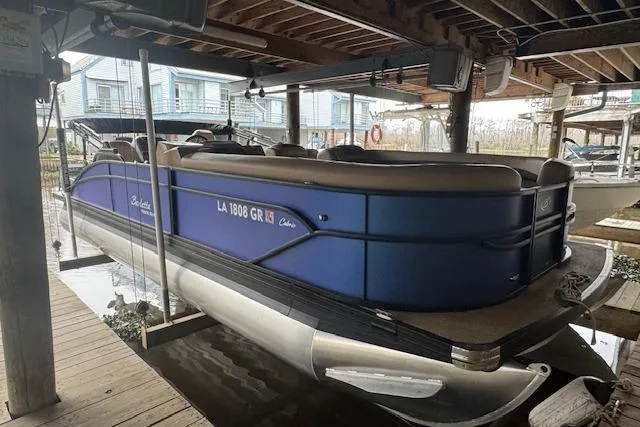 Slide: The Image of 2023 Barletta Cabrio 24CC pontoon boat docked under a wooden shelter. - 6