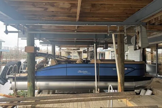 Slide: The Image of 2023 Barletta Cabrio 24CC pontoon boat docked under wooden shelter. - 8