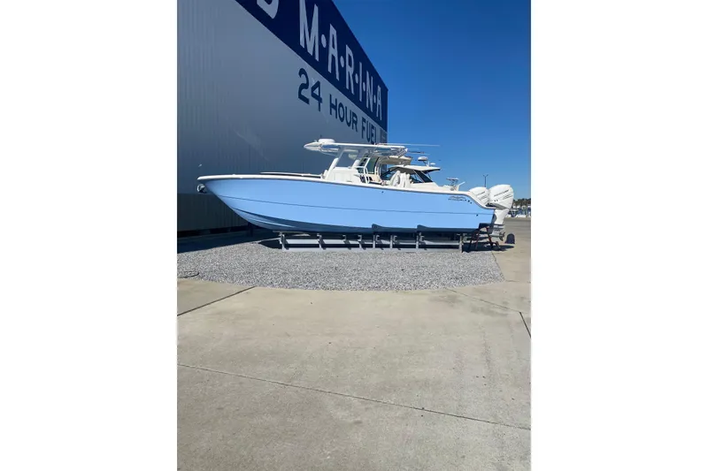 Slide: The Image of 2023 Invincible 33 Catamaran in marina, light blue hull, parked on gravel. - 2