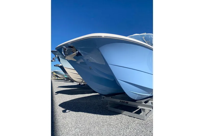 Slide: The Image of 2023 Invincible 33 Catamaran with sleek blue hull on trailer, under clear sky. - 6