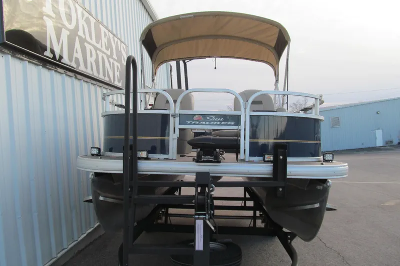 Slide: The Image of 2024 Sun Tracker Bass Buggy 16 XL Select pontoon boat at a marine dealership. - 2