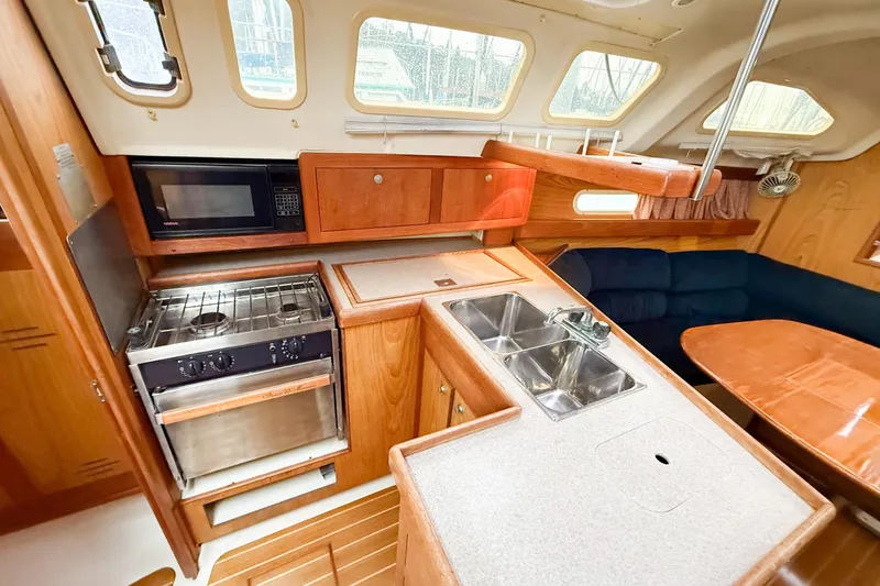 Slide: The Image of Interior of 2001 Hunter 340 sailboat kitchen with stove, microwave, and seating area. - 12