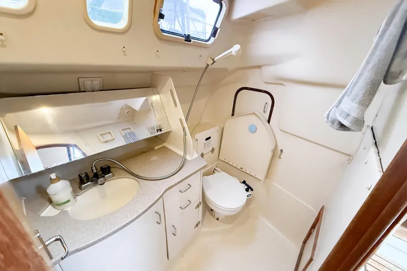 Slide: The Image of Bathroom interior of a 2001 Hunter 340 sailboat, featuring a sink, mirror, and toilet. - 18