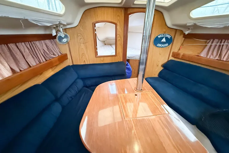 Slide: The Image of Interior of a 2001 Hunter 340 sailboat with blue seating and wooden table. - 9