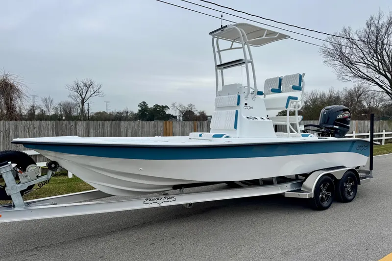 The Image of 2026 Shallow Sport 24 Modified V boat on trailer, white and blue design. - 1