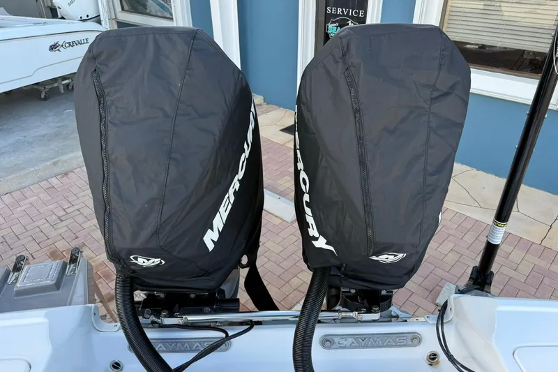 Slide: The Image of 2022 Caymas 28 HB Twin with covered Mercury outboard engines, docked near a service area. - 9