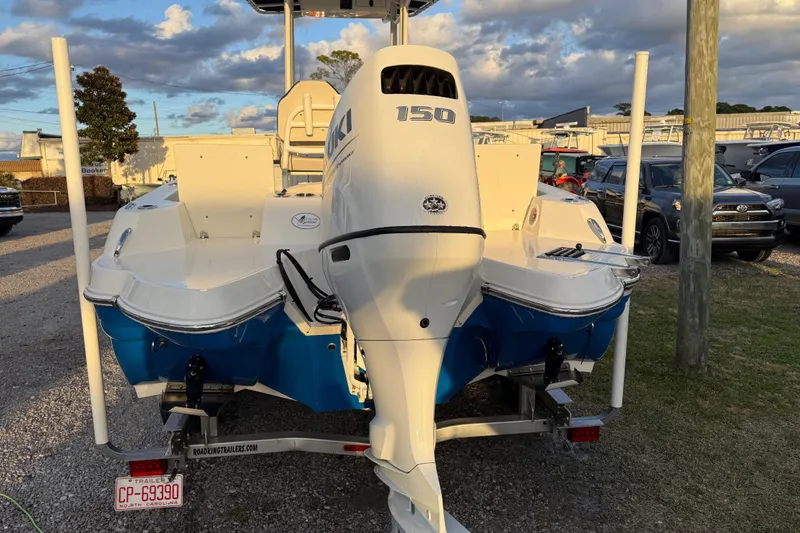 Slide: The Image of 2022 Stingray 216 CC boat with Suzuki 150 engine on trailer, parked outdoors. - 12