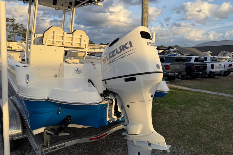 Slide: The Image of 2022 Stingray 216 CC boat with Suzuki 150 outboard motor, parked on a trailer. - 13