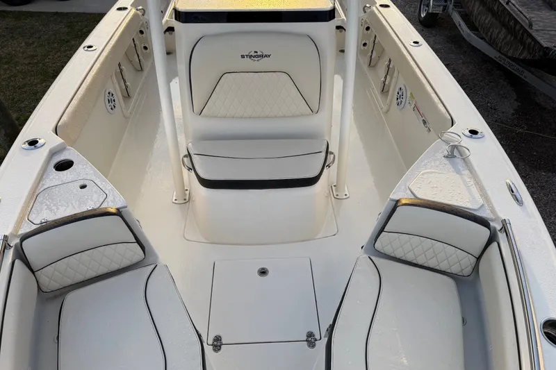 Slide: The Image of 2022 Stingray 216 CC boat interior with white cushioned seating and storage compartments. - 20