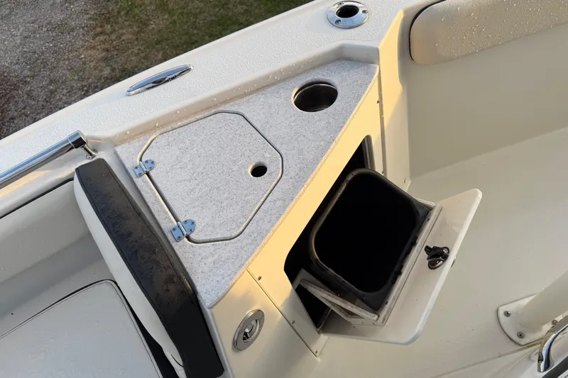 Slide: The Image of 2022 Stingray 216 CC boat interior with storage compartment and cup holder. - 24