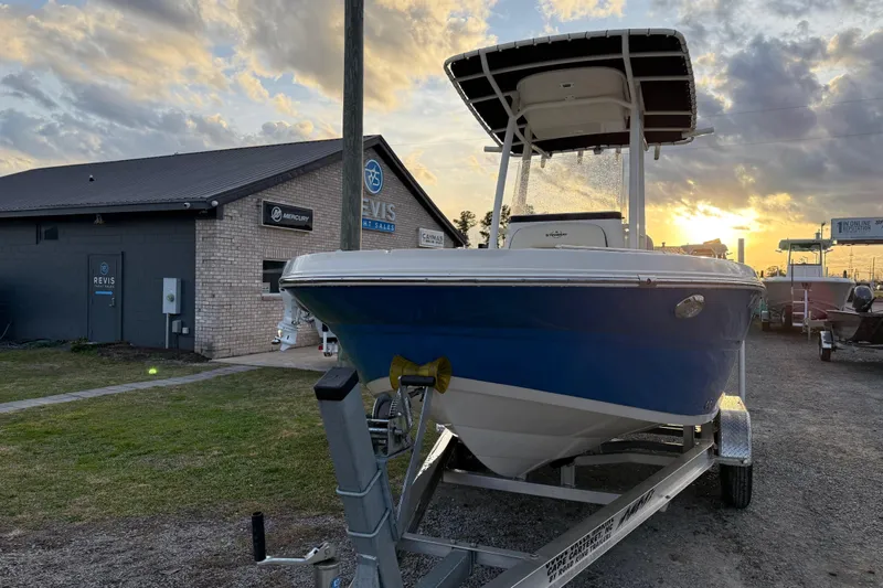 Slide: The Image of 2022 Stingray 216 CC boat on trailer at sunset near Revis Boat Sales building. - 4