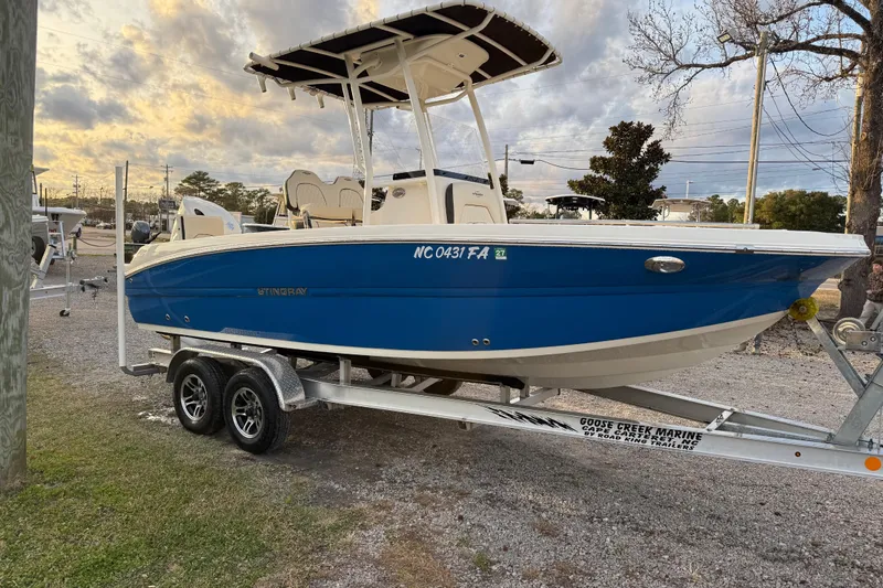 Slide: The Image of 2022 Stingray 216 CC boat on trailer, blue hull, parked outdoors. - 7