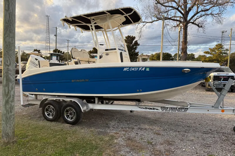 Slide: The Image of 2022 Stingray 216 CC boat on trailer, blue hull, parked outdoors. - 8