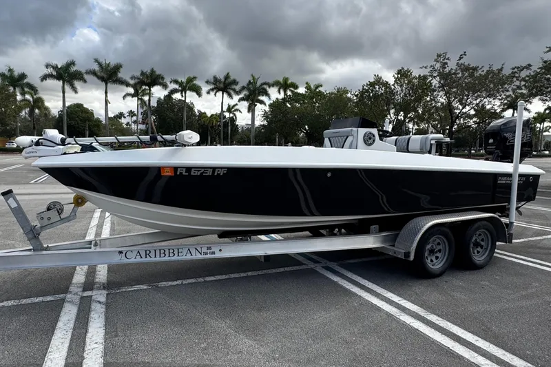 Slide: The Image of 2010 Paramount Sportfisherman 21' boat on trailer, parked under cloudy sky with palm trees. - 2