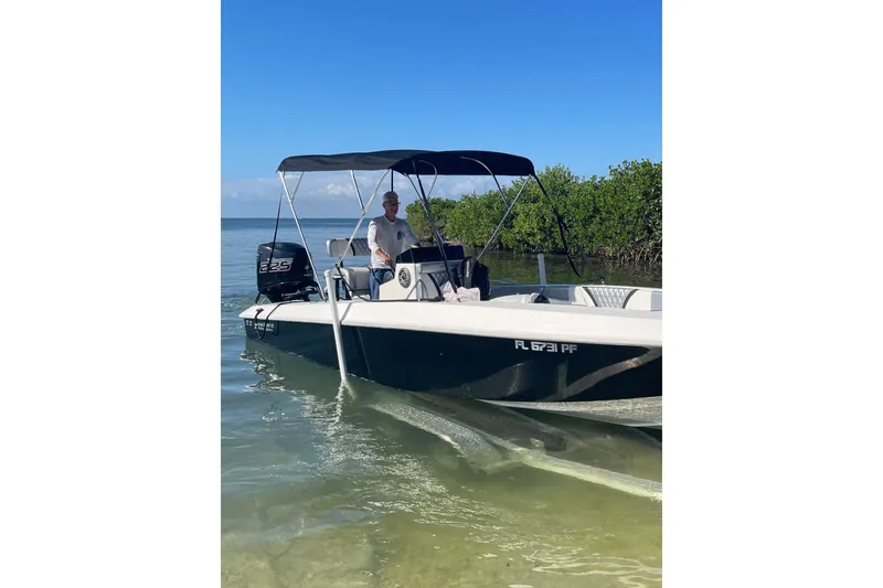 Slide: The Image of 2010 Paramount Sportfisherman 21' boat on calm water, with canopy and outboard motor. - 57