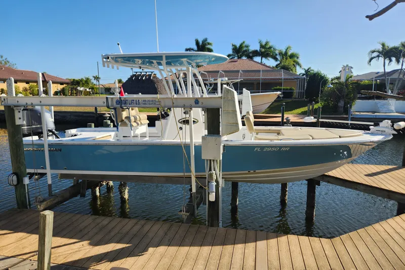 Slide: The Image of 2018 Sportsman Masters 247 Bay Boat on lift, docked in sunny waterfront setting. - 1