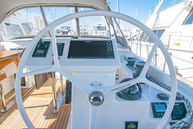 Slide: The Image of Steering wheel of 2021 Bavaria C45 yacht with navigation controls in a marina setting. - 13