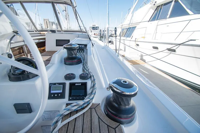 Slide: The Image of 2021 Bavaria C45 yacht deck with winches and navigation controls in a marina setting. - 25
