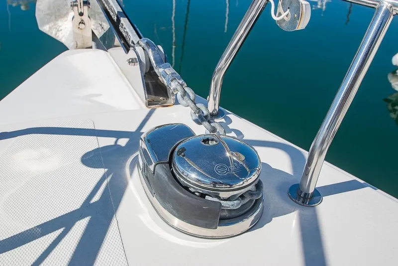 Slide: The Image of Anchor chain mechanism on 2021 Bavaria C45 yacht, reflecting sunlight on calm water. - 82