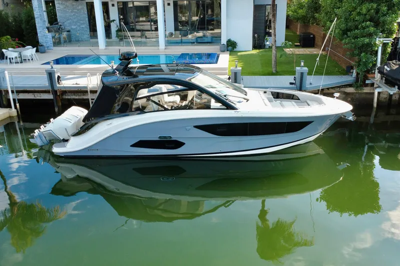 The Image of 2022 Sea Ray Sundancer 370 Outboard docked by a modern waterfront home. - 0