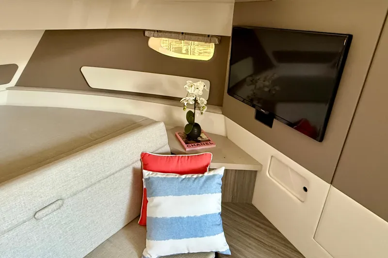 Slide: The Image of 2022 Sea Ray Sundancer 370 Outboard cabin interior with TV, cushions, and decor. - 33