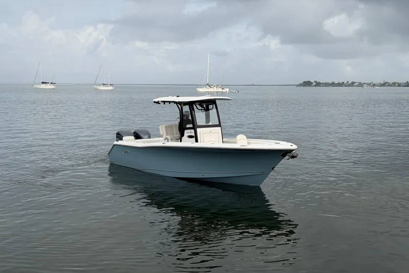 Slide: The Image of 2023 Sea Hunt Gamefish 27 boat on calm water with distant sailboats. - 2
