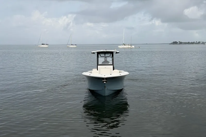 Slide: The Image of 2023 Sea Hunt Gamefish 27 boat on calm water with sailboats in the background. - 6