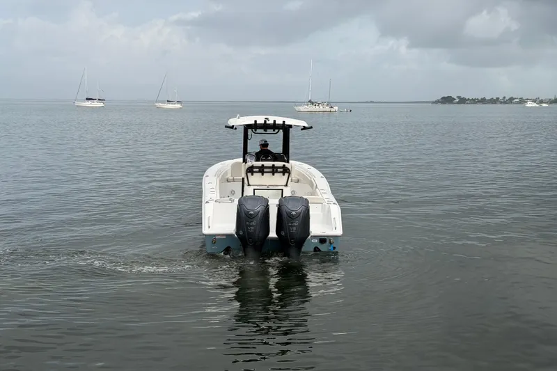 Slide: The Image of 2023 Sea Hunt Gamefish 27 boat on calm water with distant sailboats. - 7