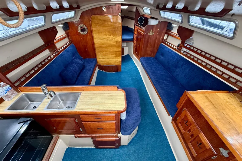 Slide: The Image of Interior of a 1982 Catalina 30 sailboat with blue seating and wooden cabinetry. - 13