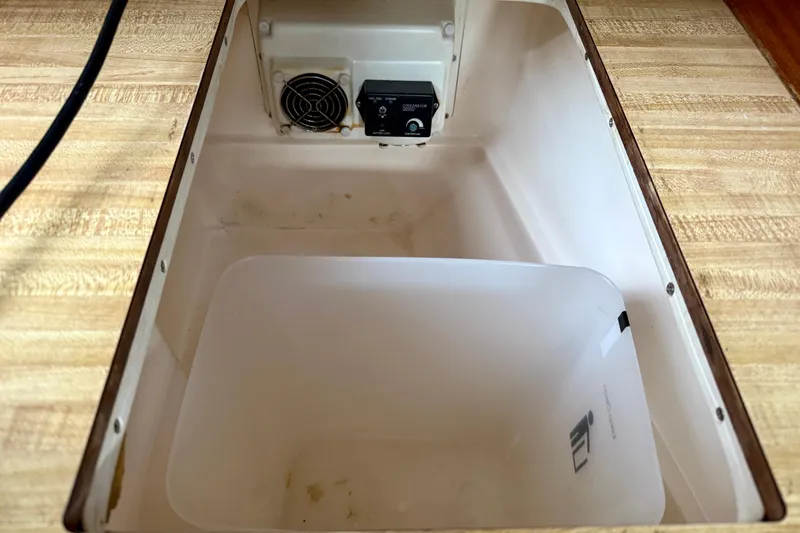 Slide: The Image of Interior of a 1982 Catalina 30 sailboat, featuring a storage compartment with a fan and control panel. - 17