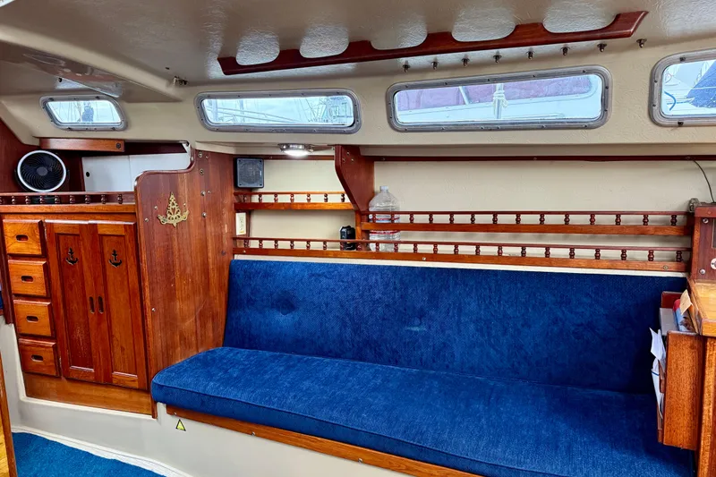 Slide: The Image of Interior of a 1982 Catalina 30 sailboat with blue seating and wooden cabinetry. - 21