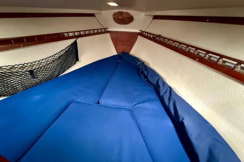 Slide: The Image of Interior cabin of a 1982 Catalina 30 sailboat with blue cushions and wooden accents. - 30