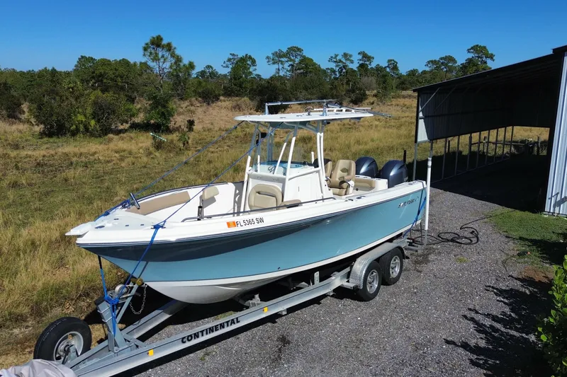 Slide: The Image of 2020 Sailfish 242 CC boat on trailer, parked outdoors near a metal shelter. - 20