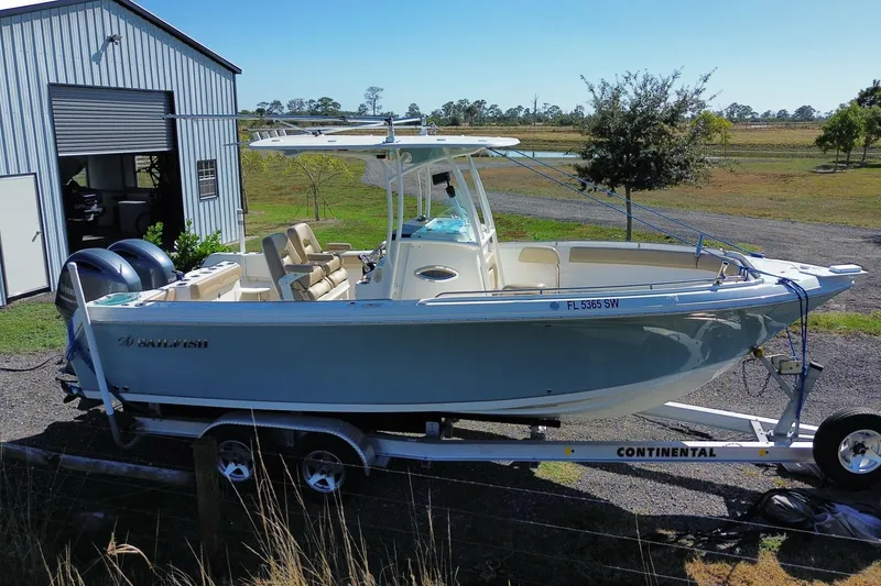 Slide: The Image of 2020 Sailfish 242 CC boat on trailer near a metal building, sunny day. - 22
