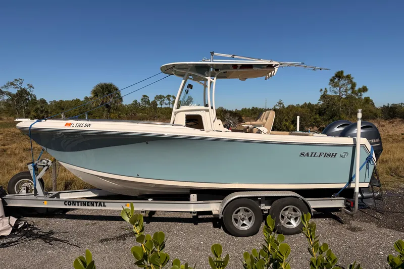 Slide: The Image of 2020 Sailfish 242 CC boat on trailer, parked outdoors under clear blue sky. - 26