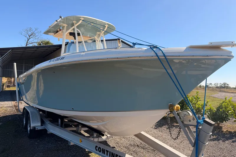 Slide: The Image of 2020 Sailfish 242 CC boat on trailer, parked outdoors under clear blue sky. - 29