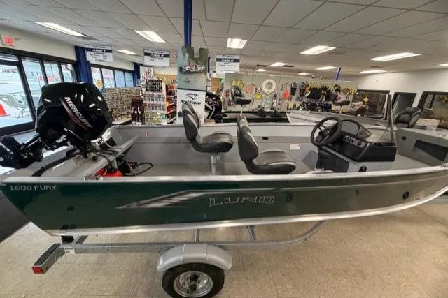 The Image of 2026 Lund 1600 Fury SS boat displayed in showroom with motor and trailer. - 0
