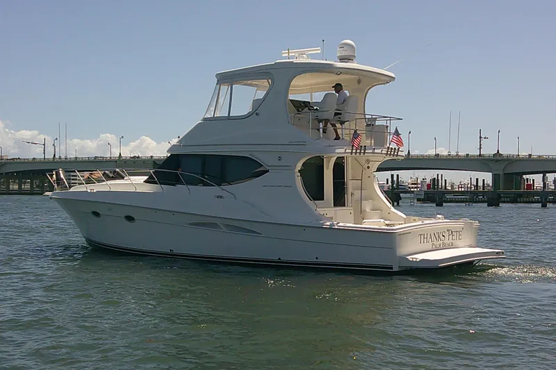 The Image of 2004 Silverton 48 Convertible yacht cruising near a bridge on a sunny day. - 0