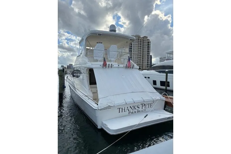 Slide: The Image of 2004 Silverton 48 Convertible yacht docked, named "Thanks Pete," with city skyline background. - 4