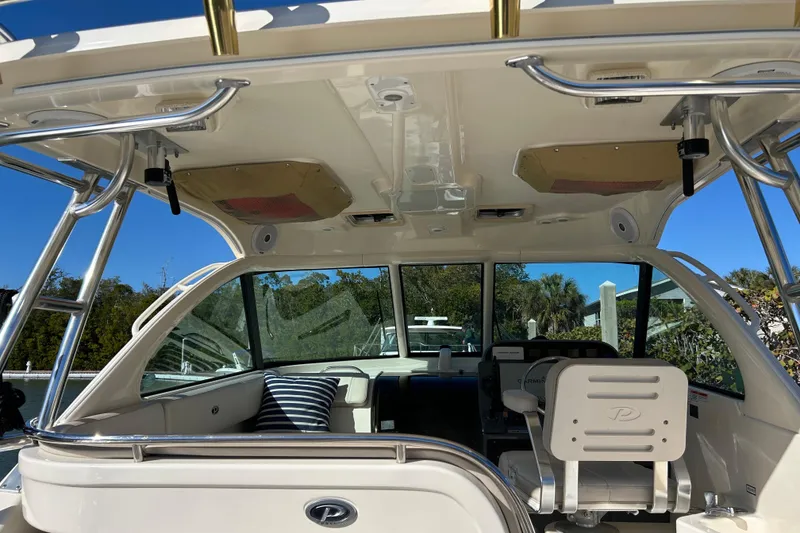 Slide: The Image of 2008 Pursuit OS 315 Offshore boat interior with seating and helm, under clear blue sky. - 14