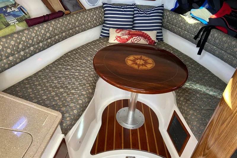 Slide: The Image of 2008 Pursuit OS 315 Offshore cabin with patterned seating and wooden table. - 16