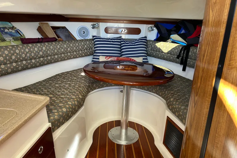 Slide: The Image of 2008 Pursuit OS 315 Offshore cabin interior with cushioned seating and wooden table. - 17